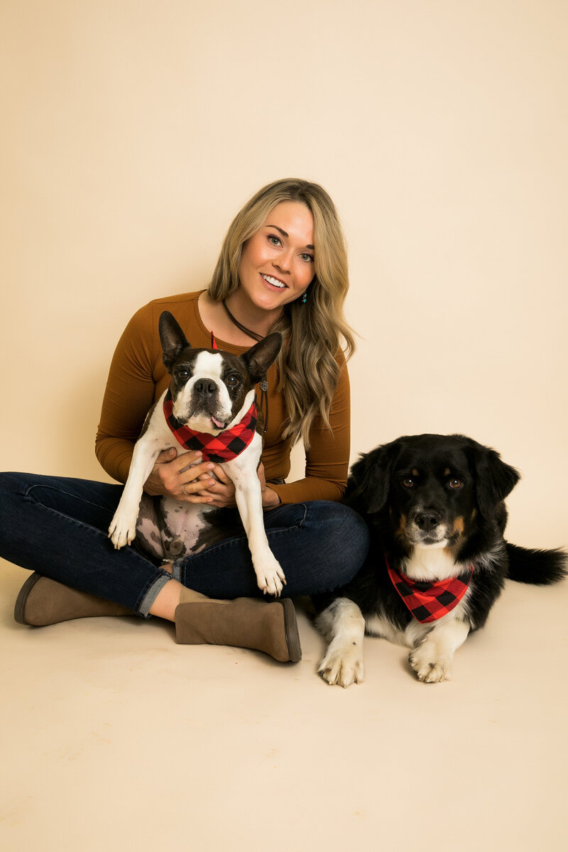 pet owner poses with two dogs  wearing plaid bandanas