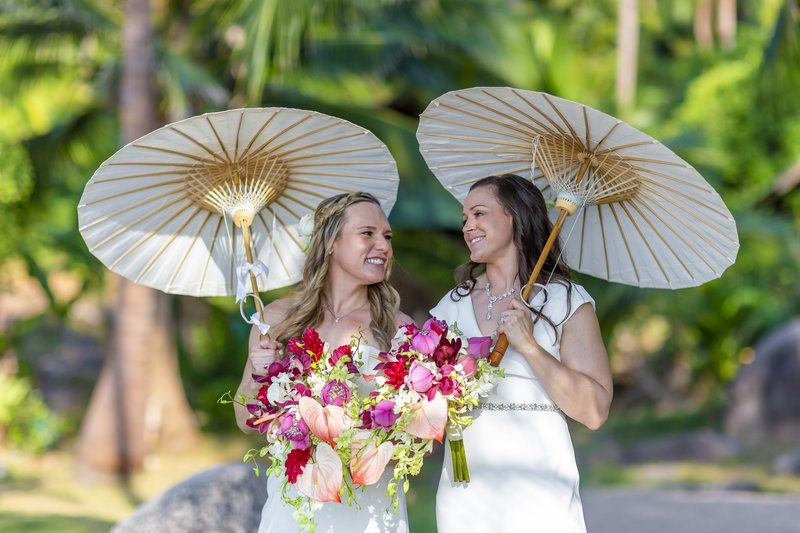 Two brides with parasols on beach