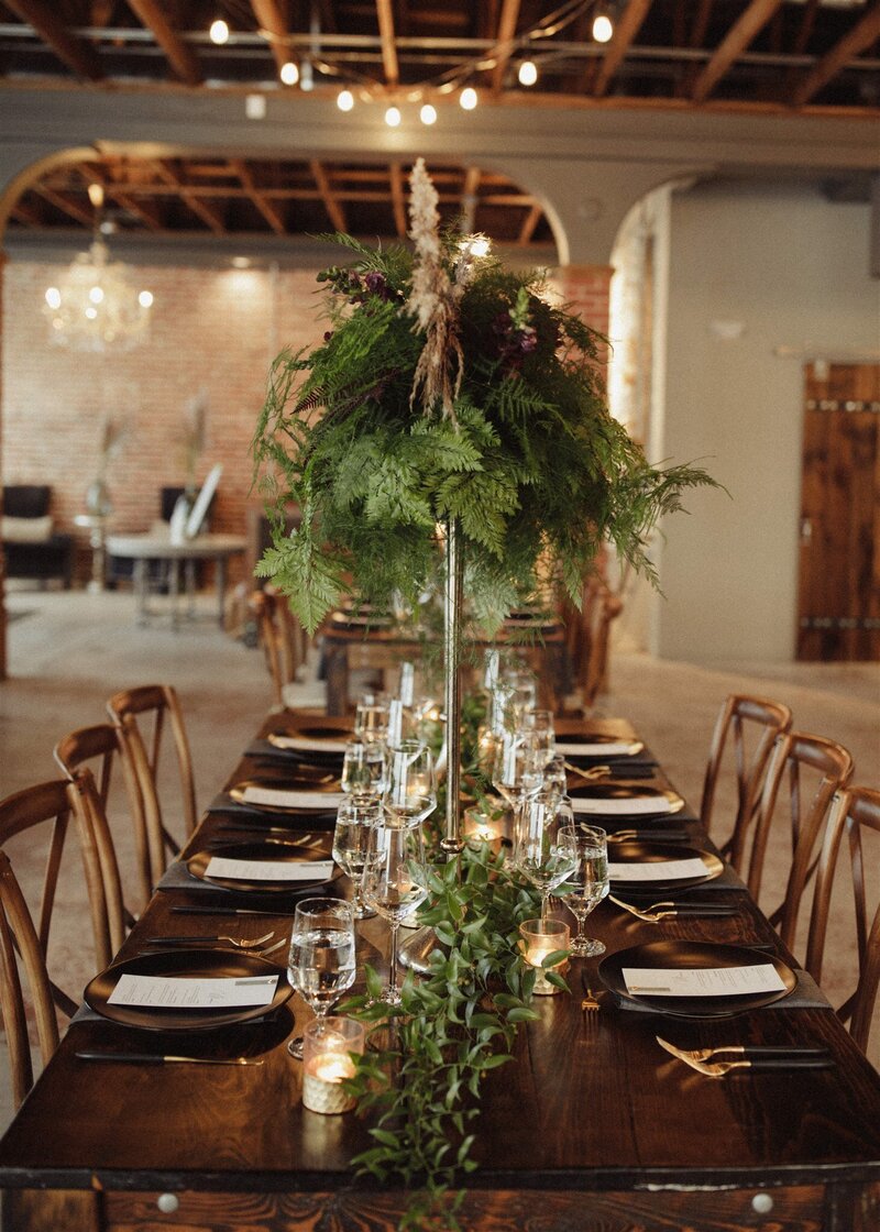 wedding reception table decorated with green foliage