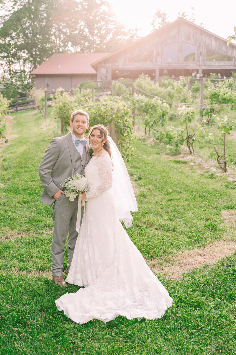 A smiling bride and groom at sunset at The Vineyard at High Holly by JoLynn Photography