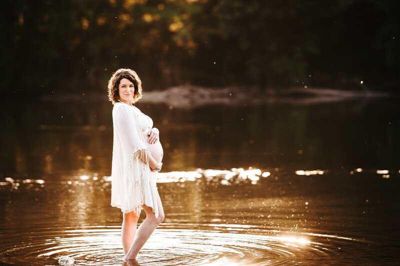 pregnant mama holding belly while standing in the river
