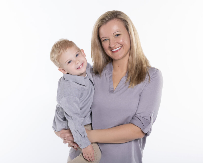 Charlotte mom and son on her hip smiling at the camera on a white backgroun, created in our Fort Mill SC portrait studio
