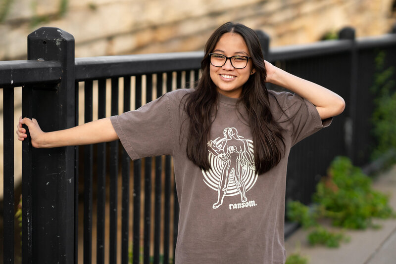 Senior girl with glasses dressed in T-shirt laughs during senior photography