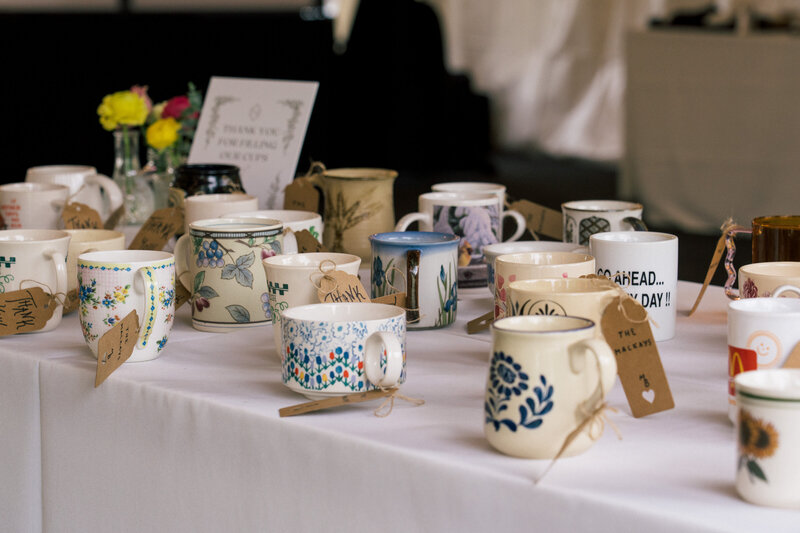 Table display of handcrafted ceramic mugs used as wedding favors, photographed by wedding photographer Niko Coric - Lumen Clarity Media