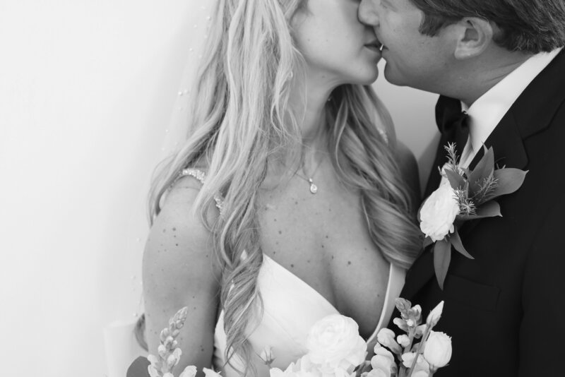 black and white photo of sexy bride kissing her husband on their wedding day close up