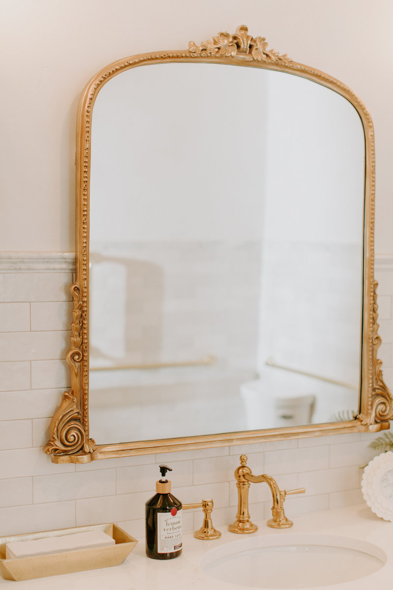 Studio bathroom details featuring a gold framed mirror, sink and decor