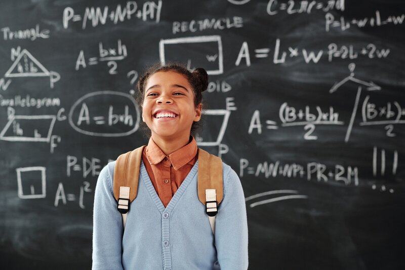 student smiling in front of blackboard