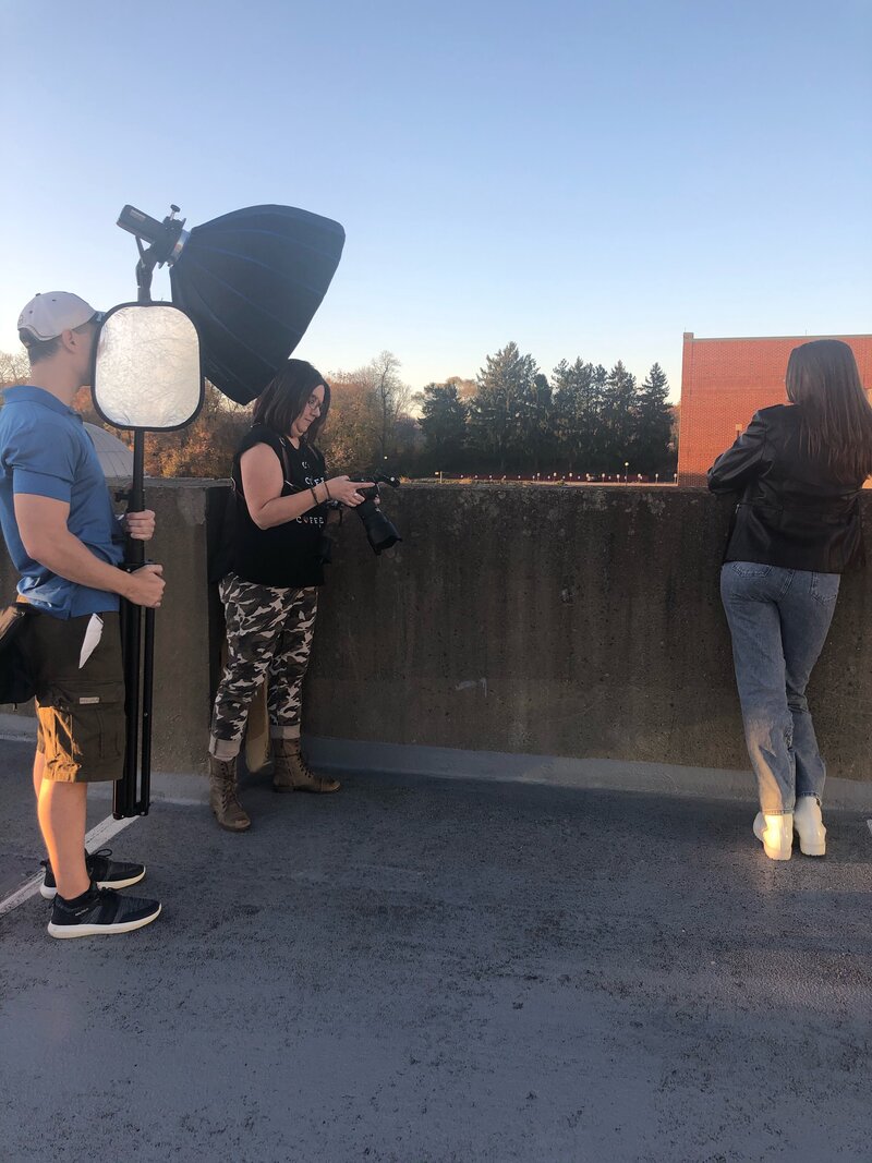 Photo shoot of senior girl leaning against wall on roof of parking garage
