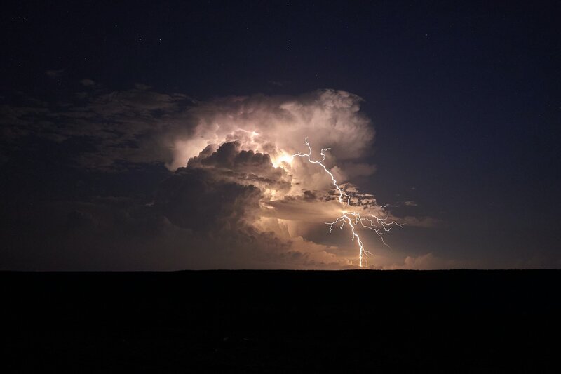 lightning bolt coming out of large cloud and striking the earth