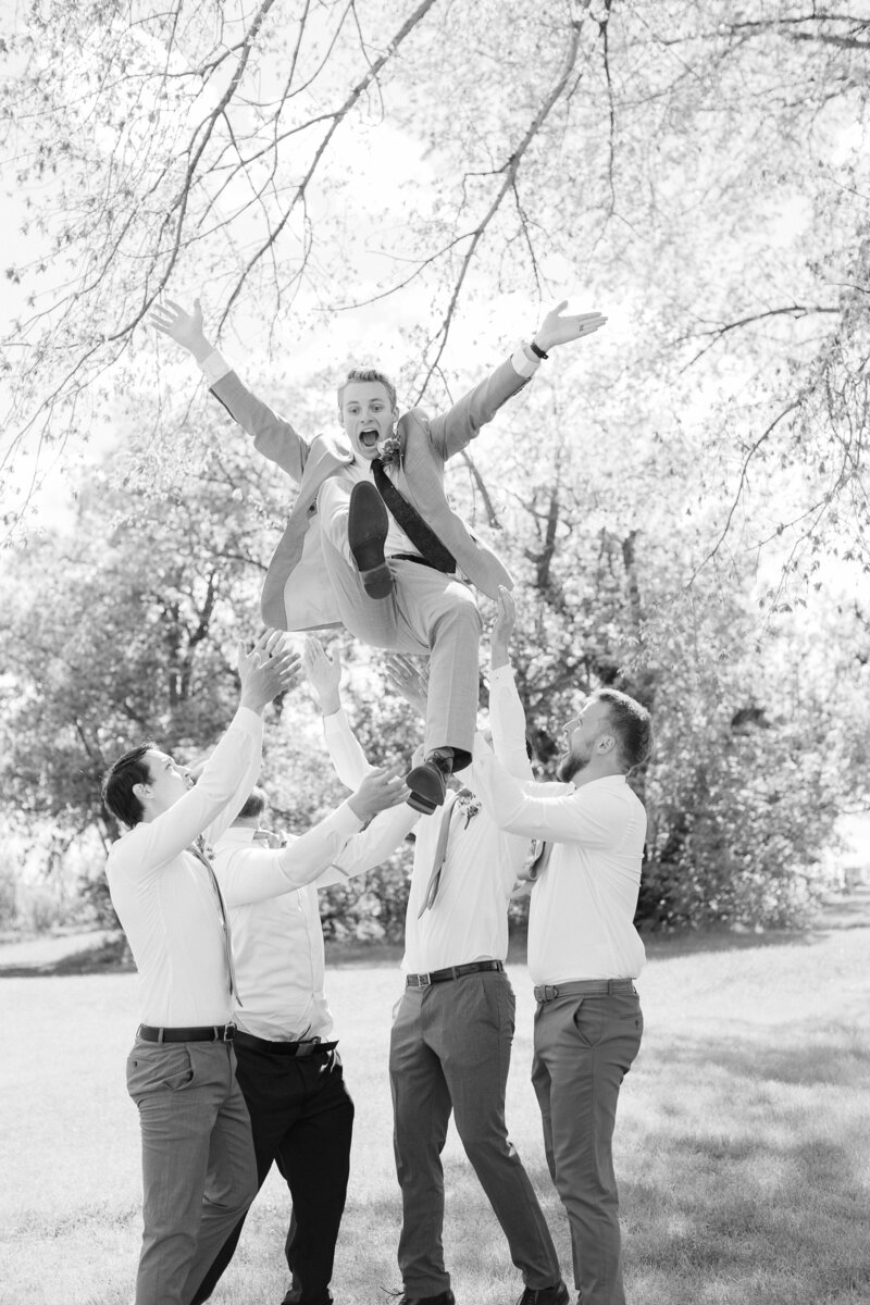 groomsmen tossing groom in air