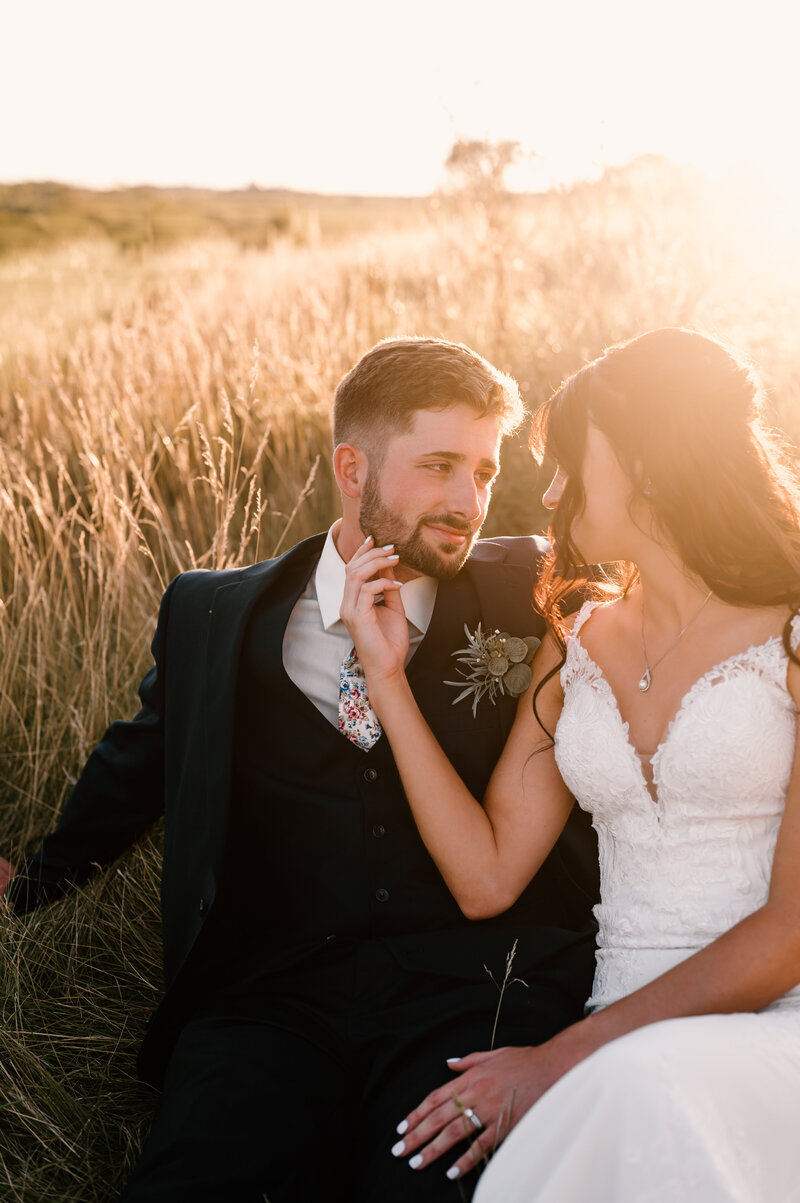 bride and groom sitting in a field