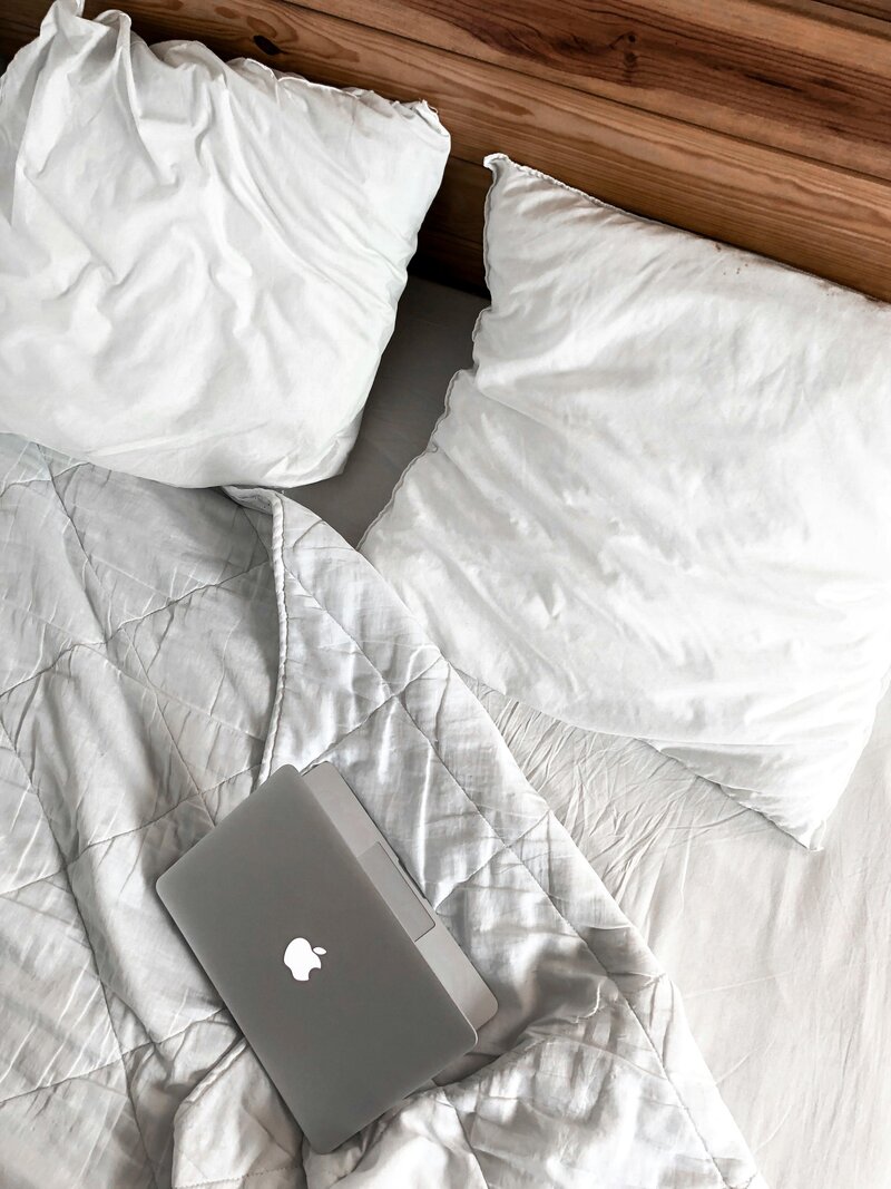 Grey Apple laptop sitting on a bed