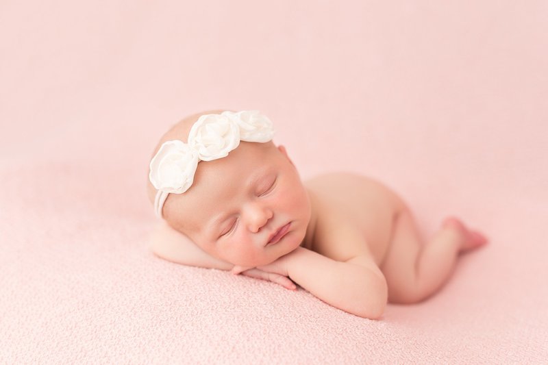 baby girl posed on pink blanket with white headband