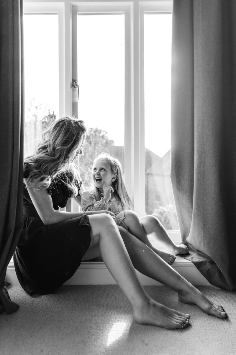 black and white mother and daughter window light