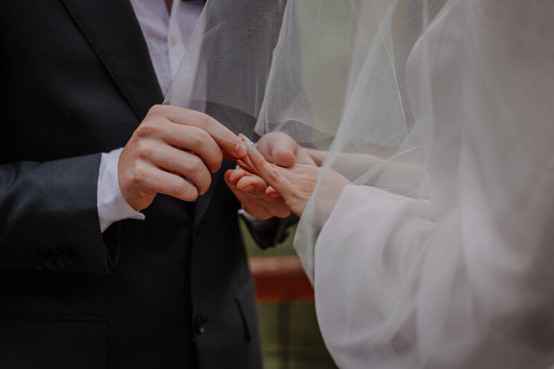 Groom putting wedding ring on bride's finger