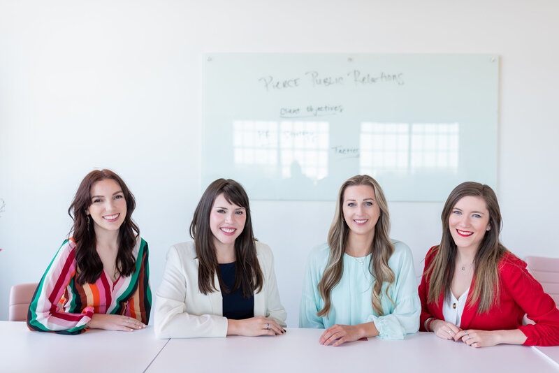 Four women in blazers sit at a table