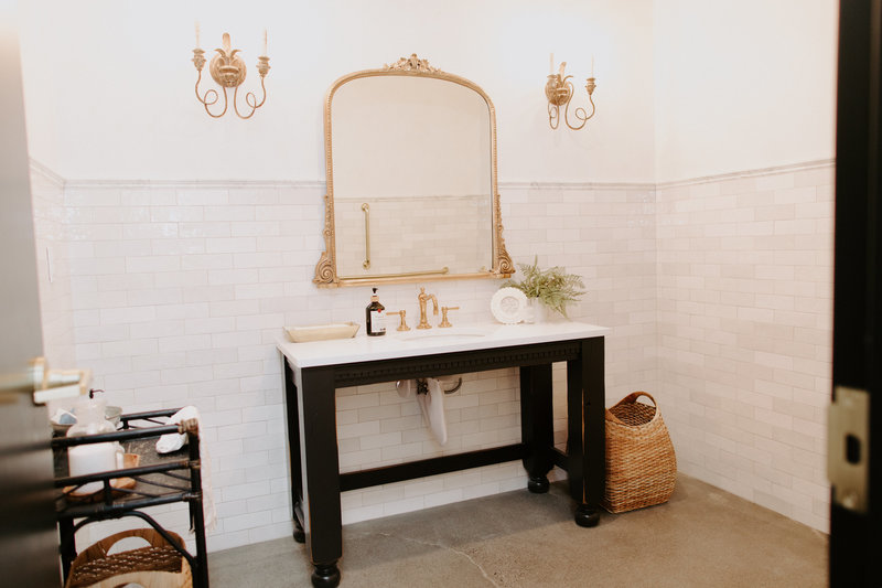 Studio Bathroom with gold mirror, gold scones, and decor