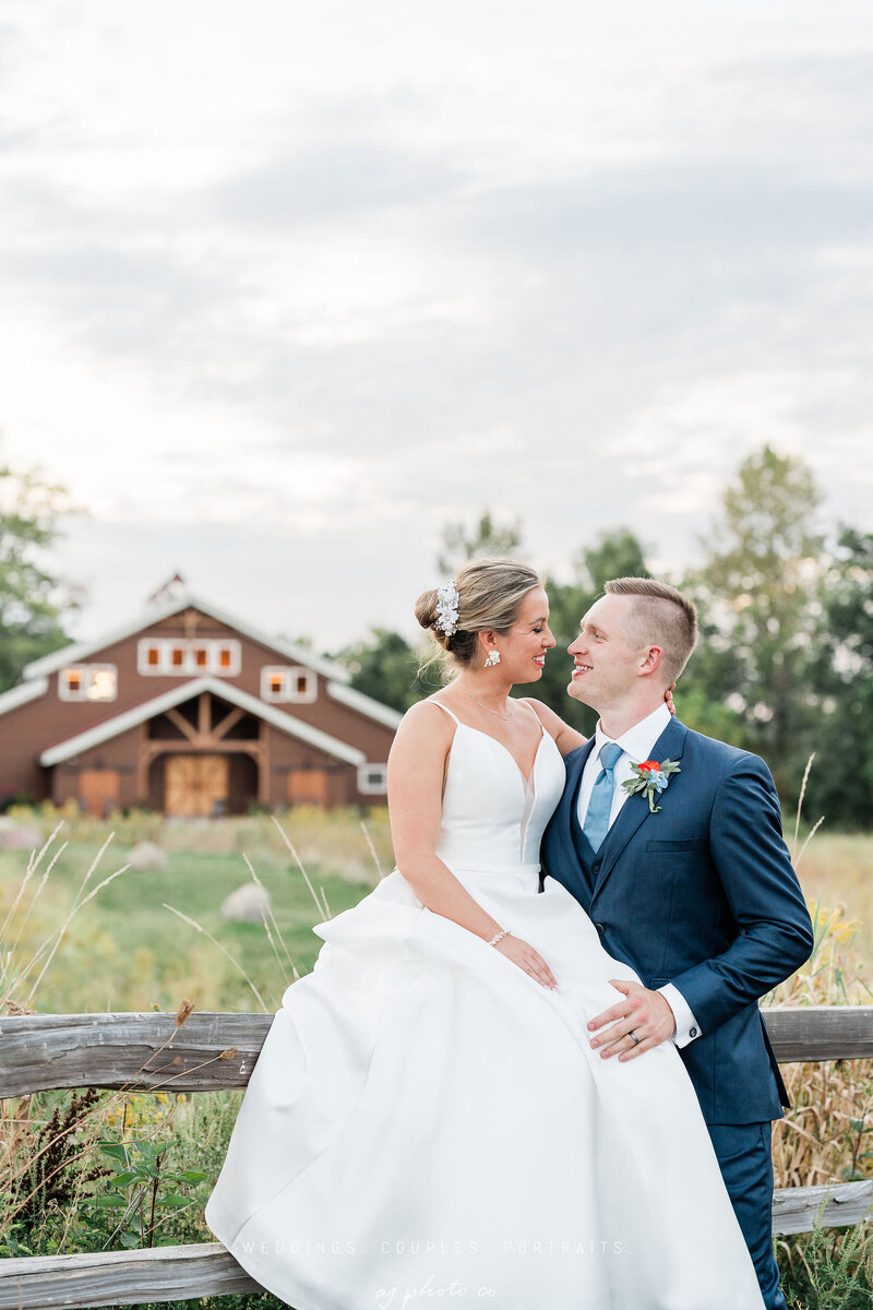 bride and groom smiling at each other outside the barn at barnwood events in madison, winconsin.