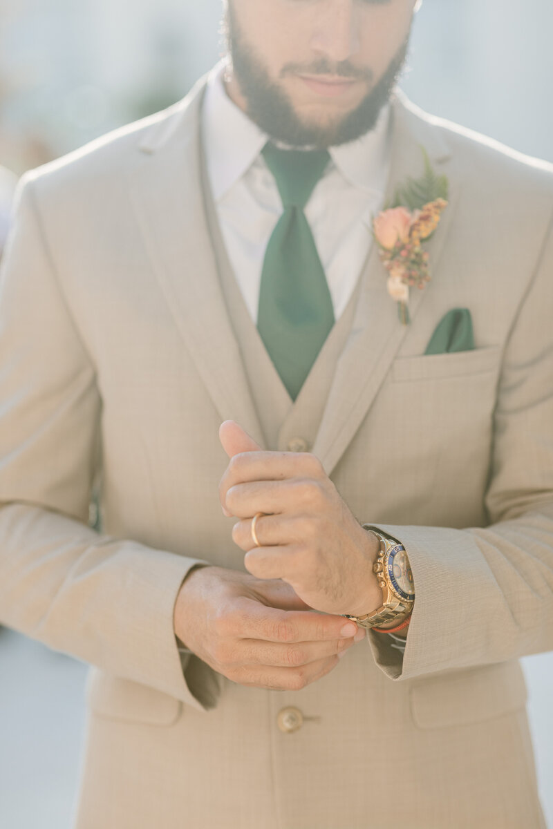 Groom adjusts the cuff of his wedding suit