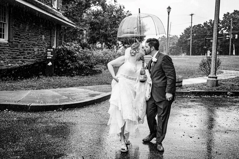 Bride and groom, kissing under an umbrella, while running in the rain in Rose tree, park and Pennsylvania
