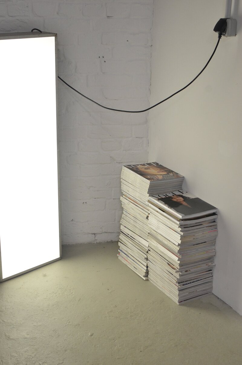 Fashion magazines stacked up beside a light box on concrete floor in a design studio