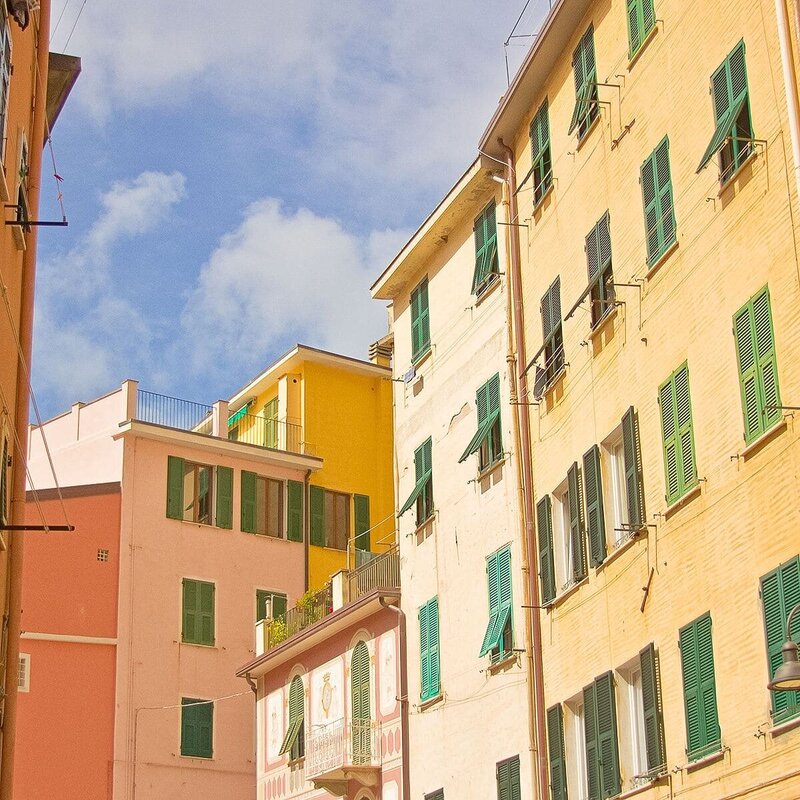 Multi colored mediterranean buildings with turquoise shutters and blue sky with white clouds