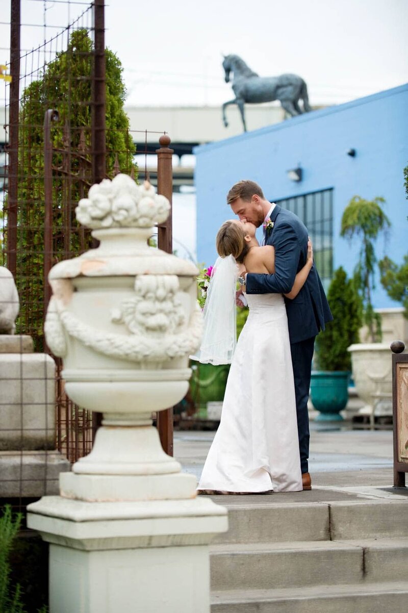 a bride and groom kiss in front of a pretty blue wall at castaway portland