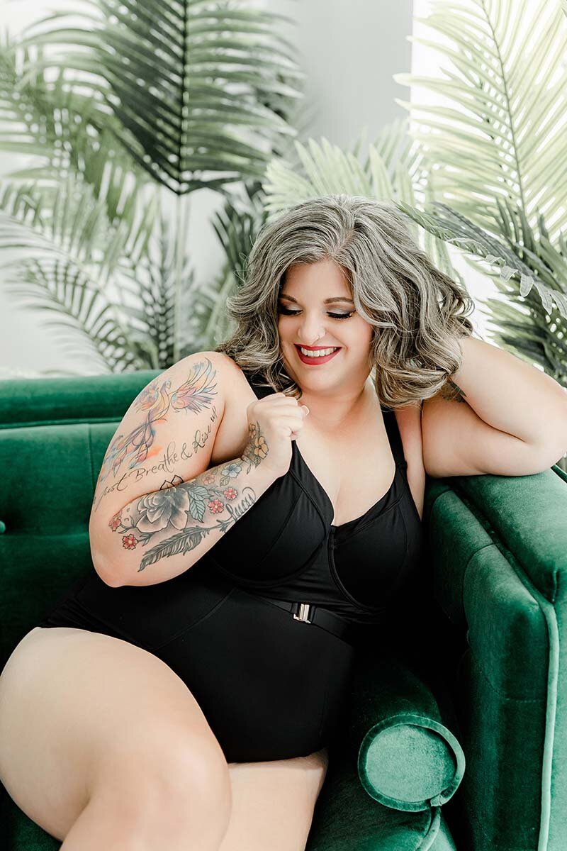 Curvy woman wearing black lace bodysuit and pink ostrich wings for boudoir portrait