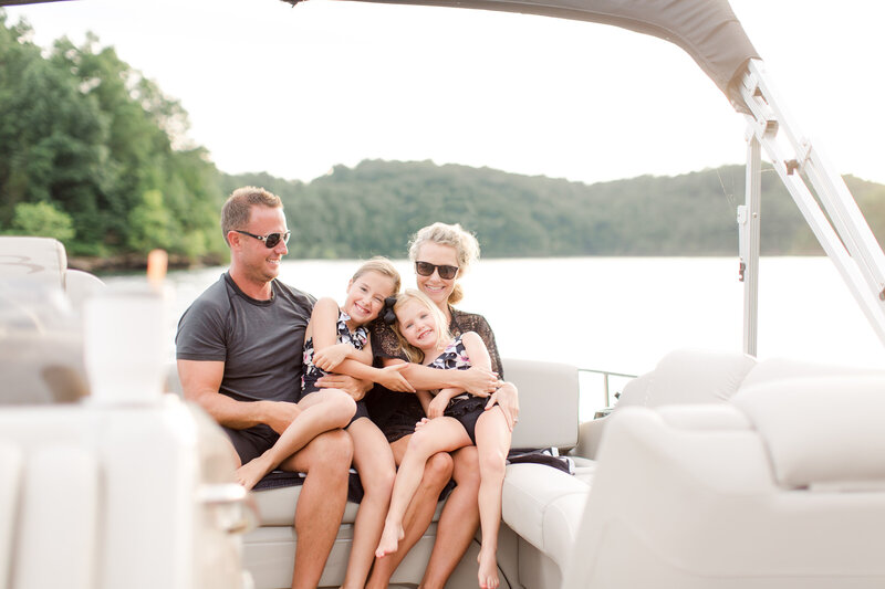 A family snuggles on a boat at a family photo session with Priscilla Baierlein on Lake Cumberland in KY.