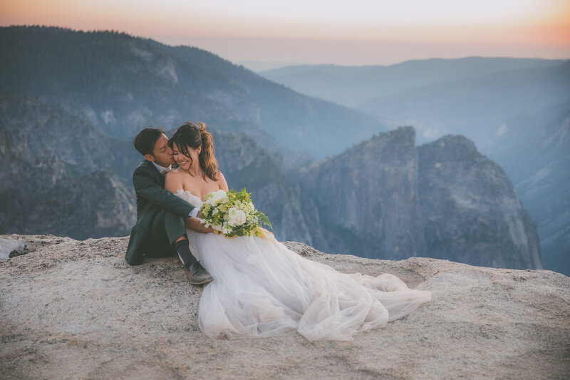 An Asian couple sits down at Taft Point to pose for elopement photos.