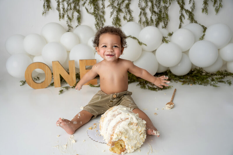 one year old boy sitting for milestone portraits in a bathtub filled with milk and cookies