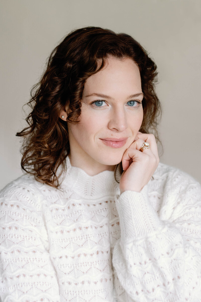Portrait of photographer Julia Luckett in white Sezane french knit sweater, looking into the camera with blue eyes with a neutral background