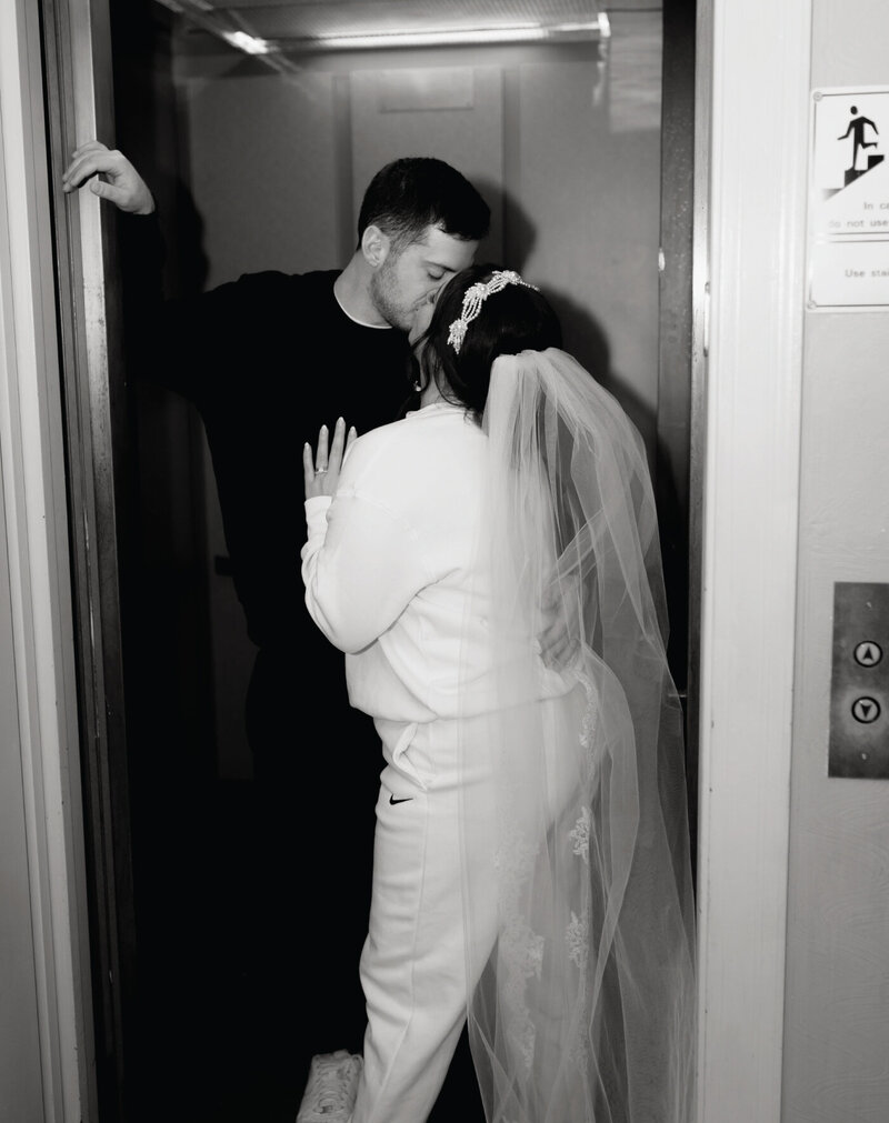 black-and-white-of-bride-kissing-groom-in-elevator