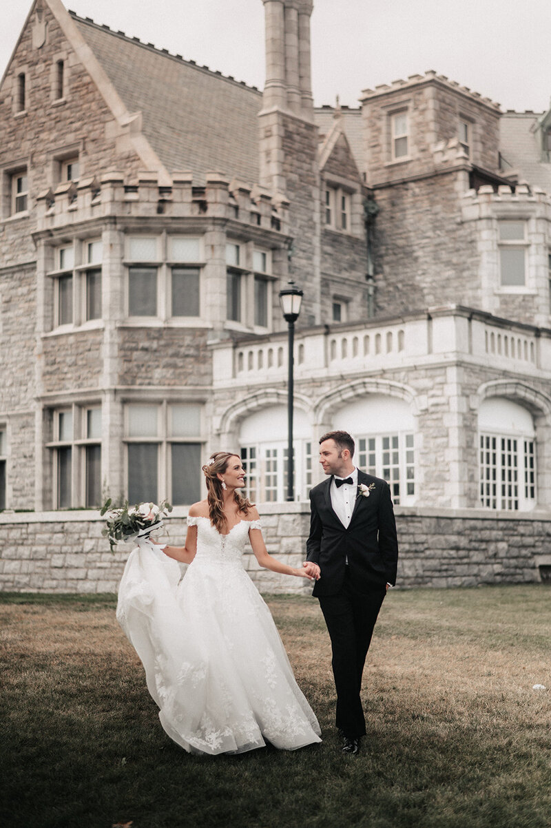 bride and groom walk hand in hand in front of their branford house wedding venue photo by cait fletcher photography