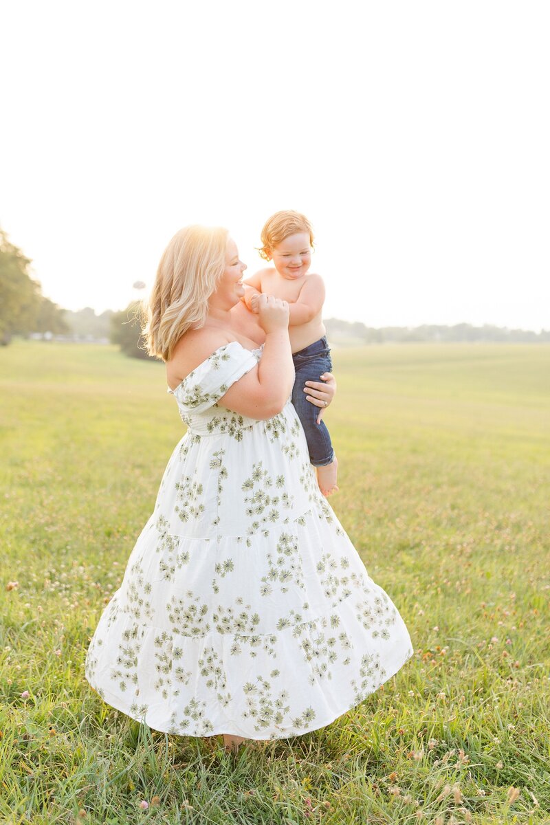 A mom twirling with toddler son during a sunset photo session at Keeneland in KY.