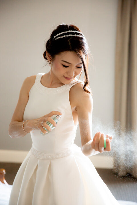 Bride spraying perfume on her wrist