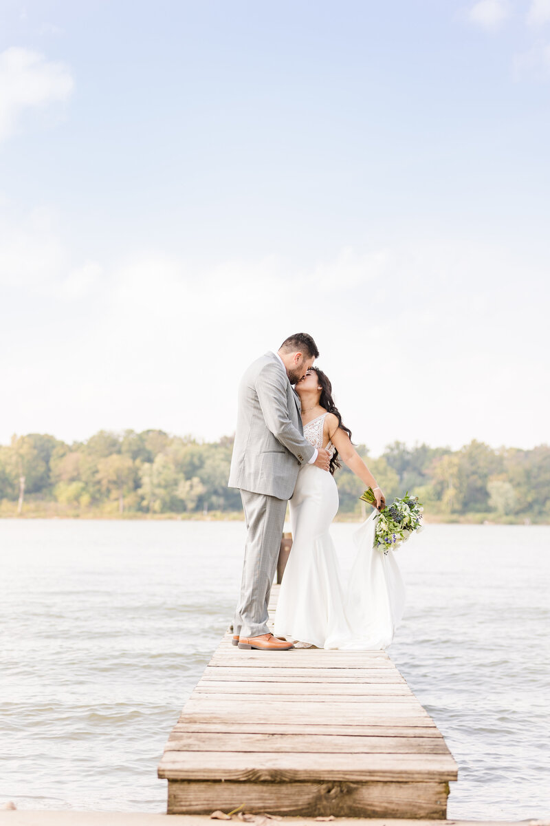 bride and groom kiss at the docks by the lake