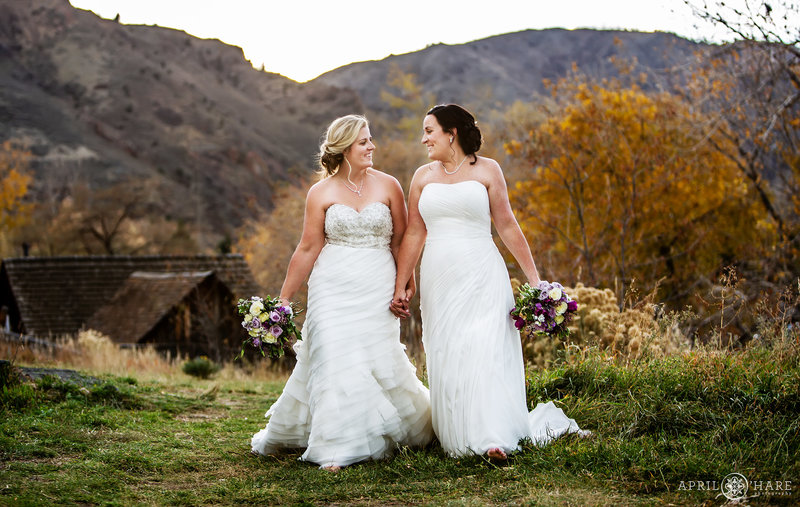 Two beautiful brides walk hand in hand on their fall wedding day at The Golden Hotel in Colorado