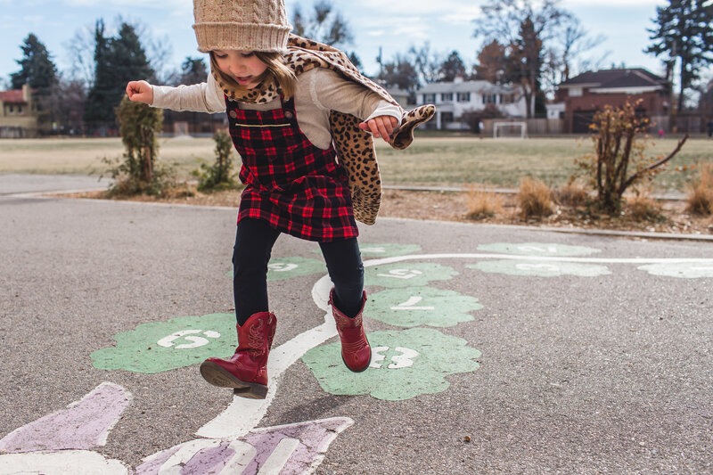Girl doing hopscotch during documentary family photography session in Denver, Colorado
