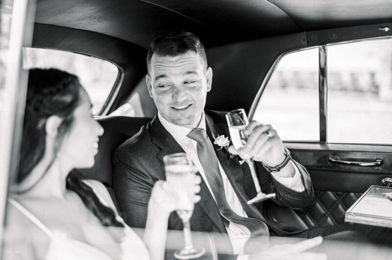 bride and groom drinking champagne in the back of a limo