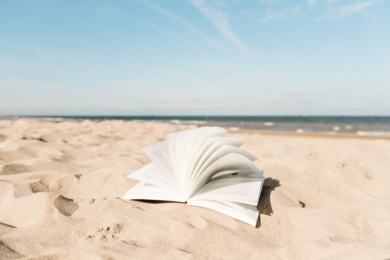 Foto van een boek dat wordt opengewaaid op het strand. Door Lia Remmelzwaal.
