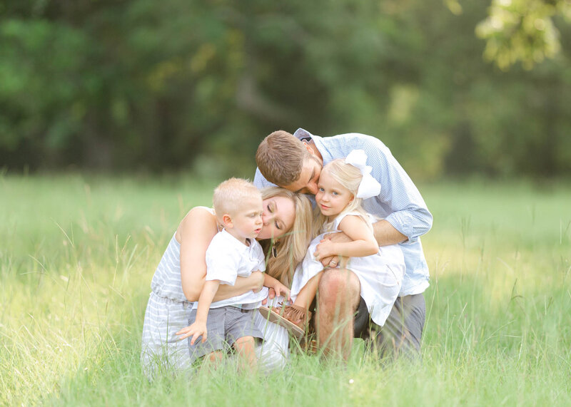 family in field hugging and kissing