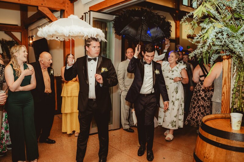 grooms walking in the barn sorrounded by their guests at barnwood events in madison, winconsin.