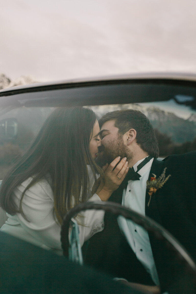 The Lovers Elopement Co - Bride and groom kiss in car at wedding elopement in Queenstown New Zealand