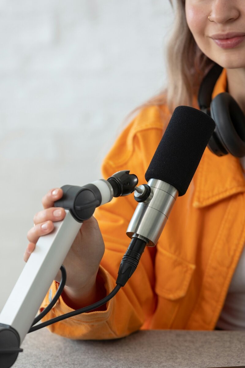 woman in orange jacket talking into podcast microphone