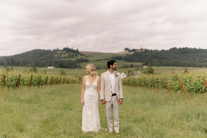 Couple Posing Holding Hands in a Vineyard - Marilee & Andrew | Bright & Colorful At the Joy Salem Oregon Wedding
