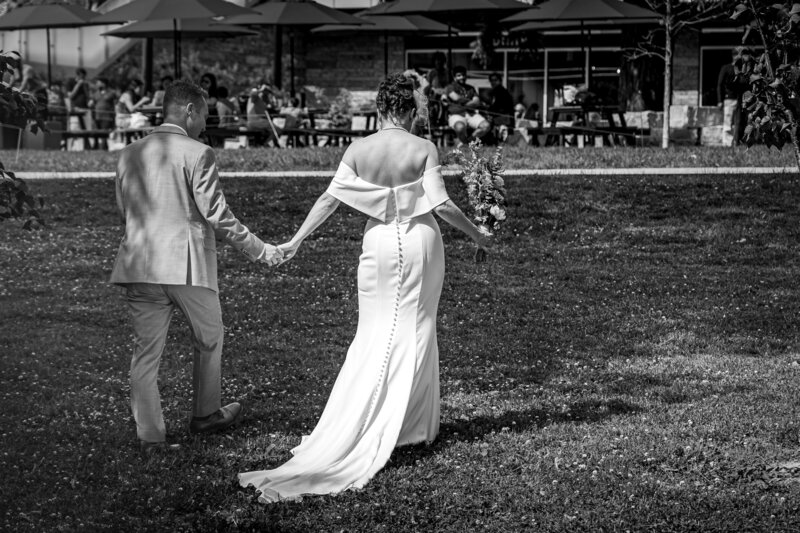 Bride and groom holding hands and laughing during candid black and white photo – photographed by wedding photographer Niko Coric – Lumen Clarity Media