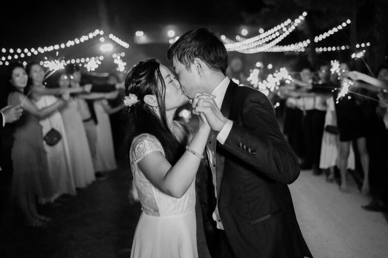 An Asian bride and groom kiss at their sparkler exit