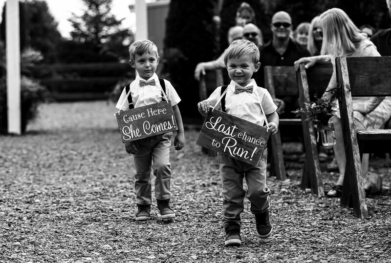 Ring bearers wearing cute signs walk down the aisle before the bride