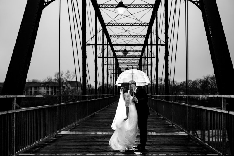 Bride and groom on wedding day at Milltown Historic District in New Braunfels, TX.  Standing on Faust Bridge